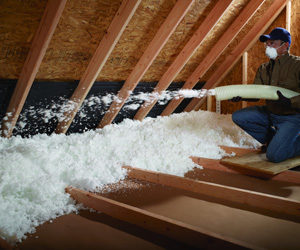 Worker installing blown in insulation