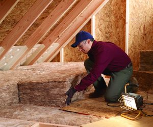 Worker installing insulation in an attic floor.