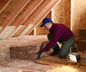 Worker installing insulation inside an attic