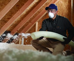 Worker installing blown insulation