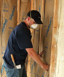Worker installing fiberglass wall insulation