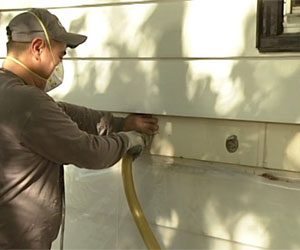 Worker installing side wall insulation