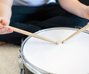 Closeup of a child's hands playing the drums.
