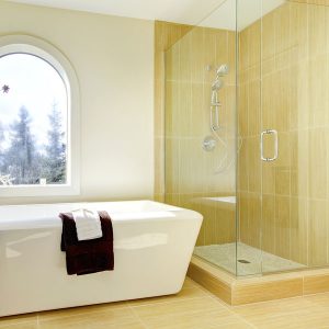 Heavy glass shower door in a bathroom with a modern bathroom and bright window.