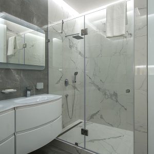 Semi frameless glass shower door in a white and grey bathroom.