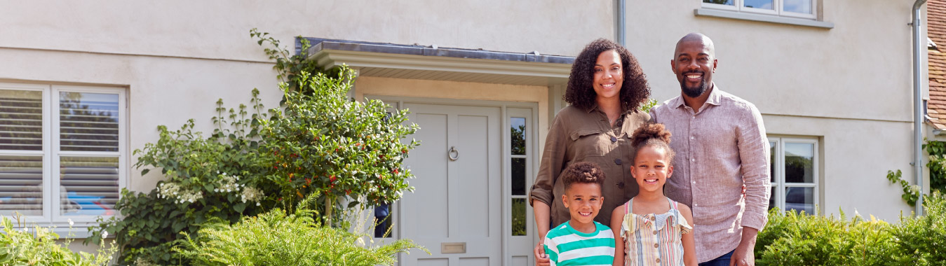 Family standing in front of a tan house.